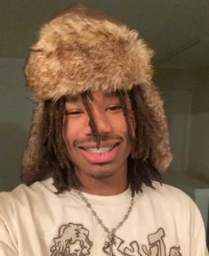 a man with dreads wearing a hat and smiling