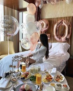 a woman sitting at a table with balloons and food