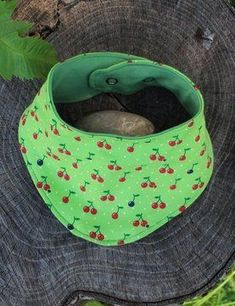 a green bandana with cherries on it sitting on top of a tree stump