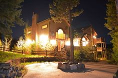 a house lit up at night with lights on and trees in the front yard area