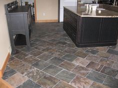 a kitchen with black cabinets and stone flooring