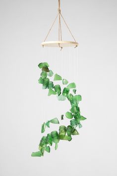 a mobile with green leaves hanging from it's sides