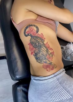 a woman with a tiger tattoo on her back sitting in a chair next to a table