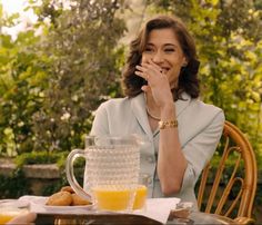 a woman sitting at a table with orange juice in front of her