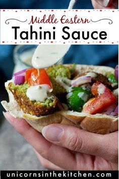 a hand holding a sandwich with dressing on it and the text middle eastern tahini sauce