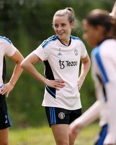 two girls in soccer uniforms standing next to each other with their hands on their hips