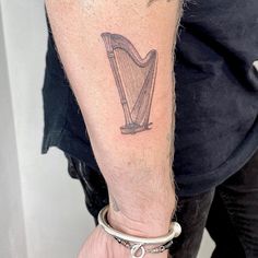 a man with a tattoo on his arm has a harp in the middle of his arm