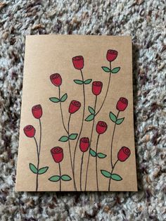 a piece of paper with red roses on it sitting on the ground next to a carpet