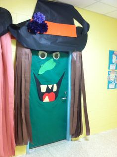 a classroom door decorated to look like a monster with long hair and big eyes wearing a hat