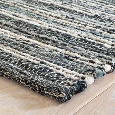 a close up of a rug on a wooden floor with a white and black stripe