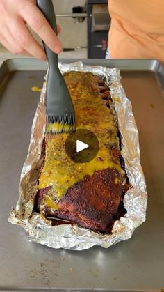 a person is using a spatula to cut meat into pieces on tin foil in the kitchen