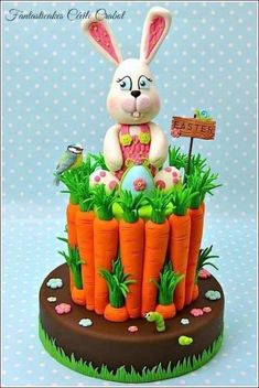 a cake made to look like a rabbit sitting on top of carrots with grass and flowers