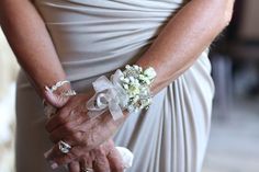 an older woman in a white dress holding a bouquet of flowers with her hands together