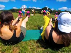 two women sitting on the ground with their feet up in the air while playing frisbee golf