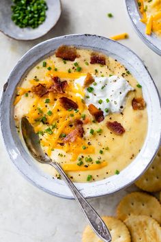 a bowl of potato soup with bacon and sour cream on top, surrounded by crackers