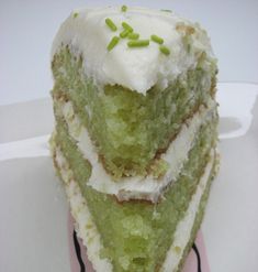 a piece of green cake with white frosting and sprinkles on top