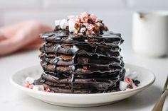 a stack of chocolate pancakes with marshmallows on top and drizzled in chocolate