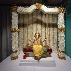 a statue of a woman sitting on a bench in front of a white backdrop with gold trimmings