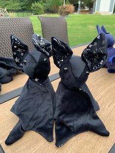 two black cloth rabbits sitting on top of a wooden table next to a blue stuffed animal