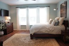 a bedroom with a bed, dressers and windows in it's center area