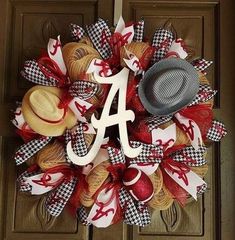 a wreath that has the letter a on it and two hats hanging from it's front door