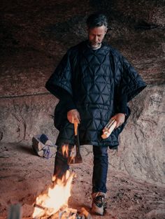 Outdoor lifestyle image of man standing over campfire wearing Down Poncho in Onyx Black from AETHER Apparel. Quilted Poncho, Poncho Fashion, Poncho Men, Mens Poncho, Life Of Adventure, Hoodie Poncho, Poncho Design, Black Down, Life Well Lived