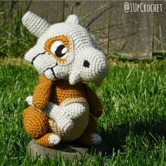 a crocheted stuffed animal sitting in the grass