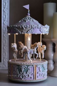 a small carousel with horses on it next to candles and other items in the background