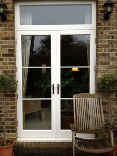 a wooden bench sitting in front of a white door with two windows on each side