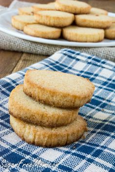 cookies stacked on top of each other on a blue and white checkered cloth next to a plate of cookies