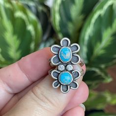 A smaller version of my double flower ring.  This cutie has two Morenci Turquosie cabs in a rustic flower setting.  She has been oxidized to bring out the details and give her a vintage feel. Measurements:  31mm x 17mm Ring Size:  8.25 Turquoise is connected to the healing energy of water, the life-giving element that sustains the planet and the origins of life itself. This energy of renewal and rejuvenation is what gives the turquoise crystal meaning. It has a unique ability to support healing intentions and overall well-being. The water-like qualities of the turquoise stone also guide you to a state of calm and tranquility, which can aid in stress-relief and the elimination of negative energies. In this way, you can also use the turquoise healing properties for energetic protection and s Handmade Flower-shaped Ring, Unique Turquoise Flower Jewelry, Adjustable Turquoise Flower Ring Gift, Bohemian Sterling Silver Flower Ring, Adjustable Bohemian Blue Flower Ring, Bohemian Silver Flower Jewelry, Turquoise Healing Properties, Flower Setting, Morenci Turquoise