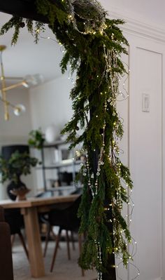 a christmas garland with lights hanging from it's side in front of a mirror