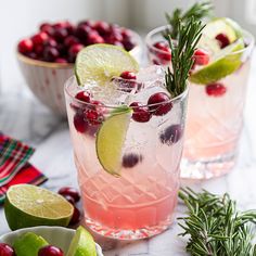 two glasses filled with cranberry lemonade, lime and rosemary garnish