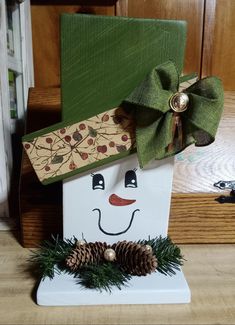 a wooden block with a snowman face and pine cones on it's head