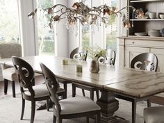 a dining room table with chairs and a chandelier hanging from it's ceiling