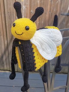 a crocheted bee sitting on top of a metal stand