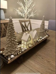 a wooden table topped with christmas trees and ornaments on top of a wooden tray covered in lights