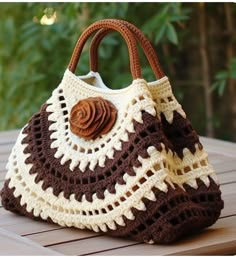 a brown and white crocheted purse sitting on top of a wooden table next to a tree