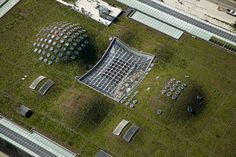 an aerial view of a green roof with several rows of solar panels on the grass