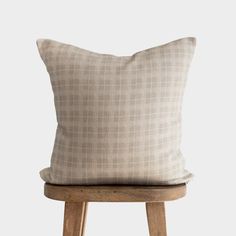 a beige pillow sitting on top of a wooden stool