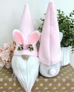 two gnomes with pink ears and white hair are sitting next to each other on a table