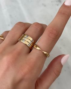 a woman's hand with three gold rings on her fingers and two diamonds in the middle