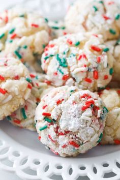 cookies with sprinkles and white frosting are on a plate, ready to be eaten