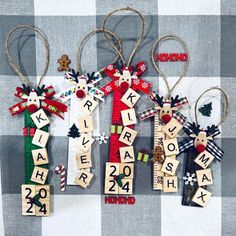 four wooden christmas ornaments hanging on a checkered tablecloth