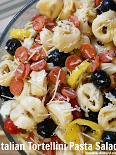 pasta salad with tomatoes, olives, and peppers in a glass bowl