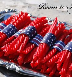 red, white and blue candy sticks with american flags on them in a silver tray