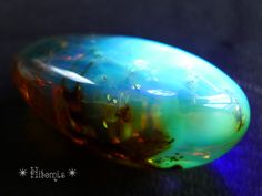 an opalite stone sitting on top of a black tablecloth covered floor with blue and green colors