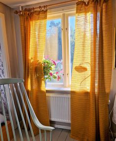 a chair sitting in front of a window with yellow drapes on it's sides