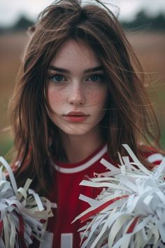 a woman with freckled hair and blue eyes wearing a cheerleader uniform is looking at the camera