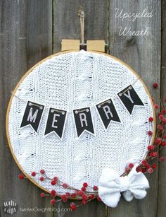 a white and black merry banner hanging from a wooden hoop with red berries around it